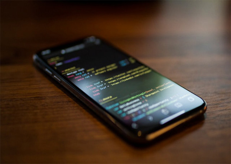 a smart phone on a  table displaying coding