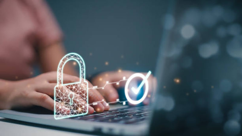 woman on a laptop with web security and a pad lock icons made up of light hovering over her laptop